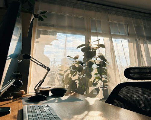 Desk near a window with sheer curtains diffusing bright sunlight